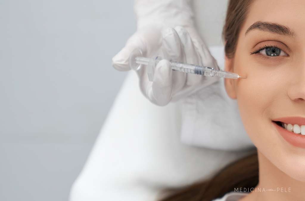 Fotografia mostra uma mulher sorrindo enquanto recebe uma aplicação de injeção próxima aos olhos por profissional com luvas, ilustrando tratamento estético com skinbooster para hidratação profunda da pele.